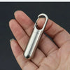 A hand holds a stainless steel travel pill box and first aid container.