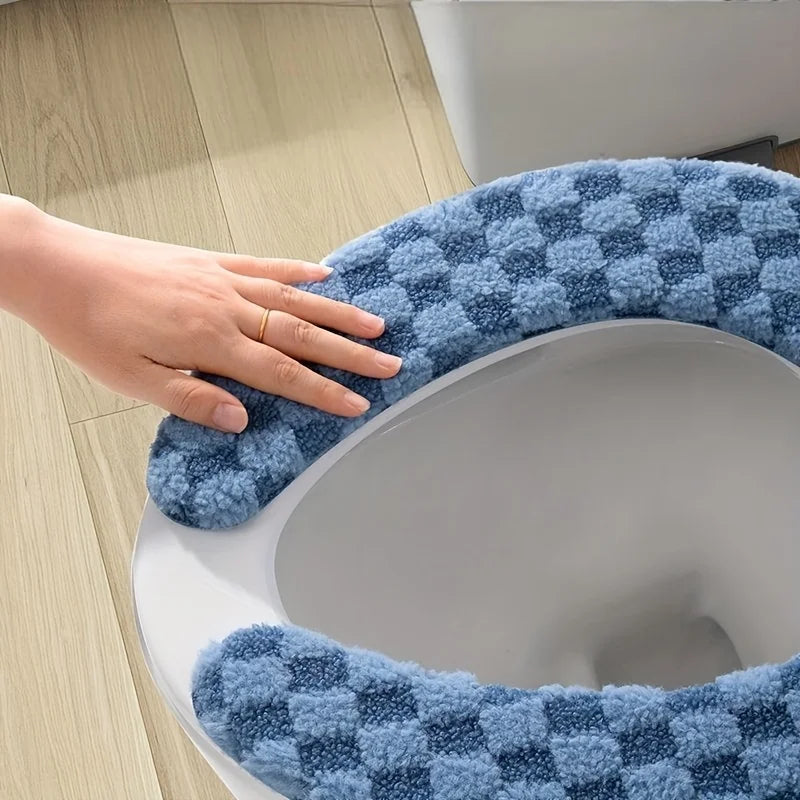 A hand is placing a blue and gray checkered fabric cushion cover onto a white toilet seat.