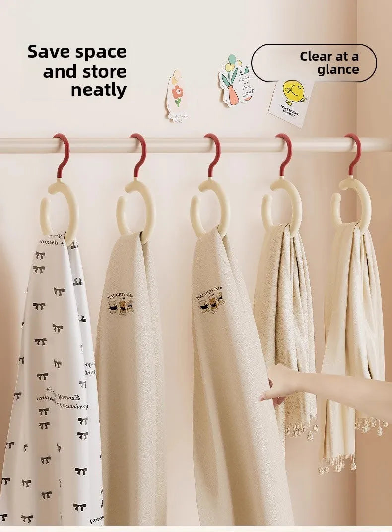 Exposition de foulards en tissu beige et blanc accrochés sur un porte-serviette blanc.