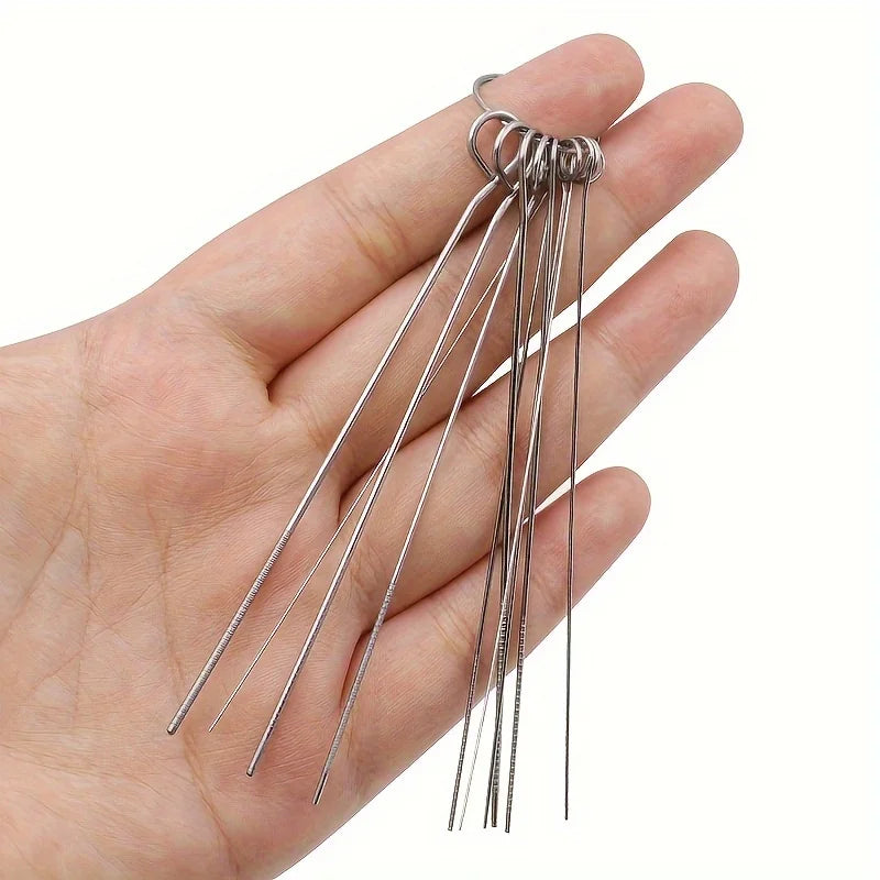 A hand holds a set of stainless steel shower head cleaning brushes with multiple thin wires.