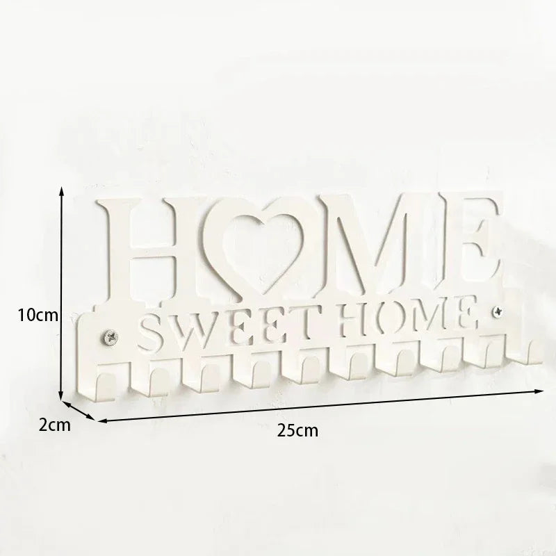 A white metal wall hook key holder with the words HOME SWEET HOME cut into the design.