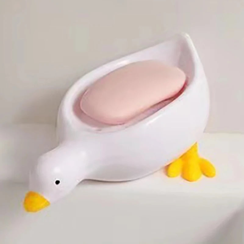 White duck-shaped soap dish with a pink soap bar on a white surface.