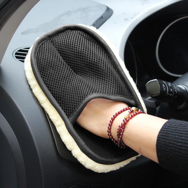 A hand wearing a soft black washing glove rests on a car interior surface.