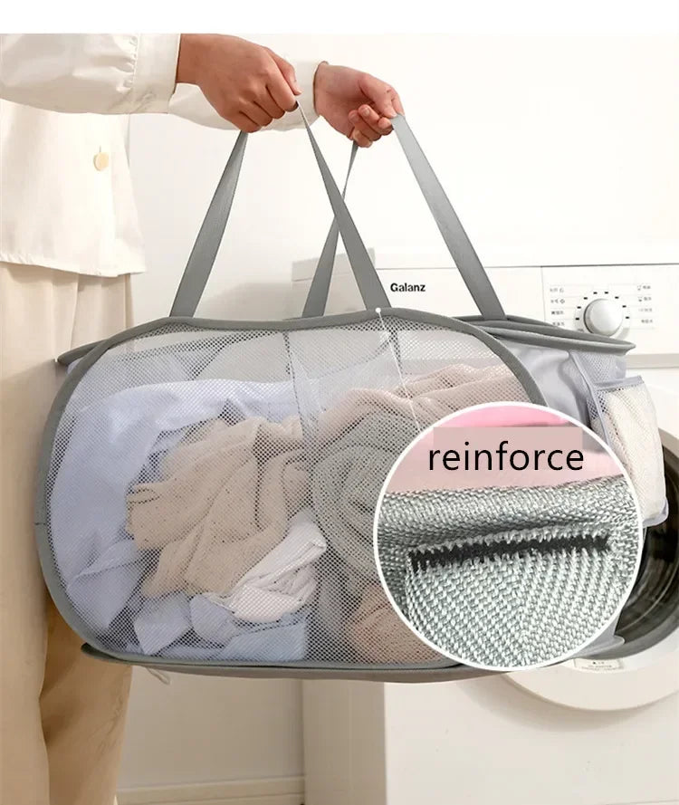 A person is holding a gray foldable mesh laundry basket filled with clothes, demonstrating its use for storage.