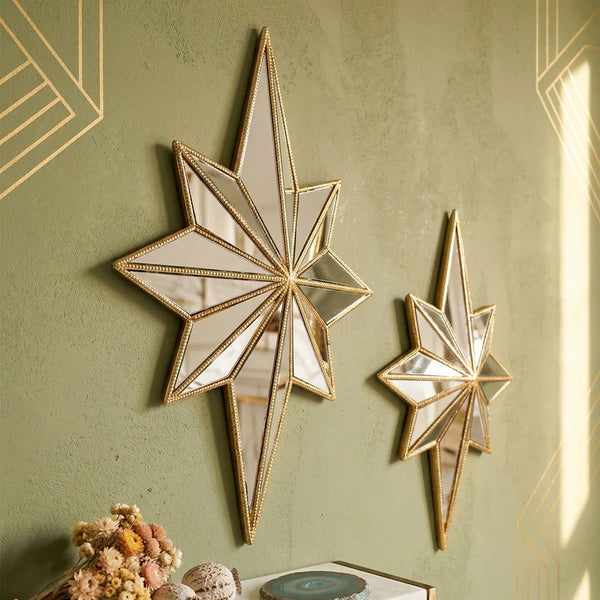 A decorative resin star wall hanging with a gold frame mounted on an olive green textured wall.