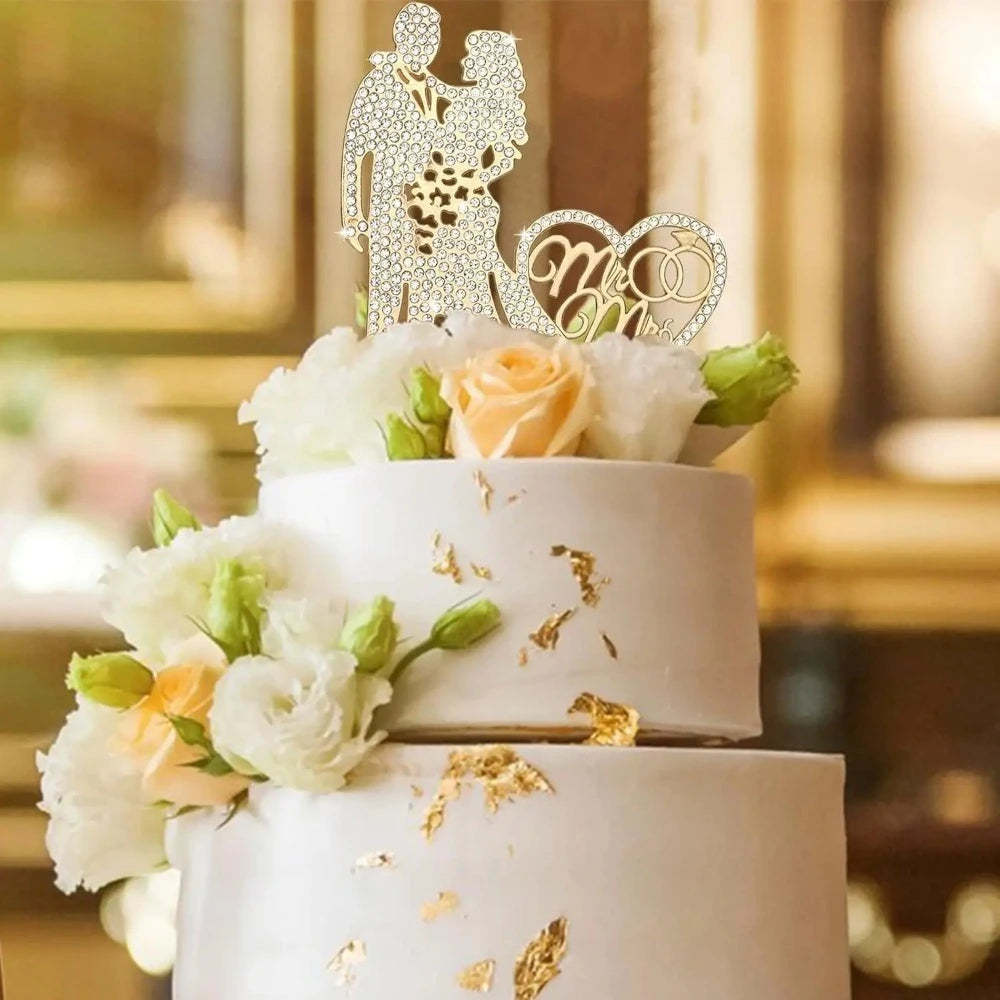 A two-tiered white wedding cake decorated with floral accents and a crystal rhinestone Mr & Mrs topper.