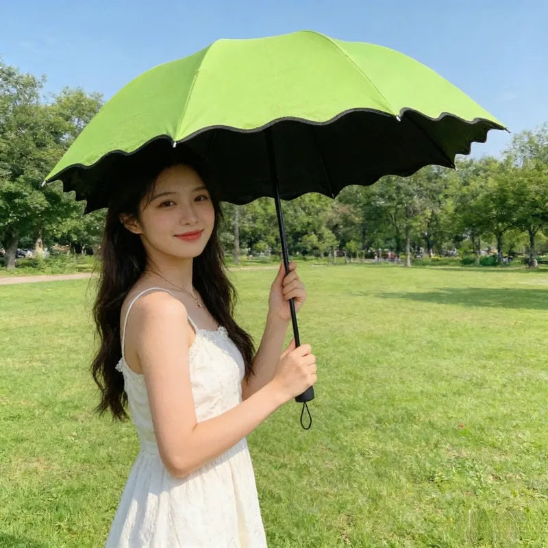 A young woman holding a bright green and black reversible umbrella in a grassy park.