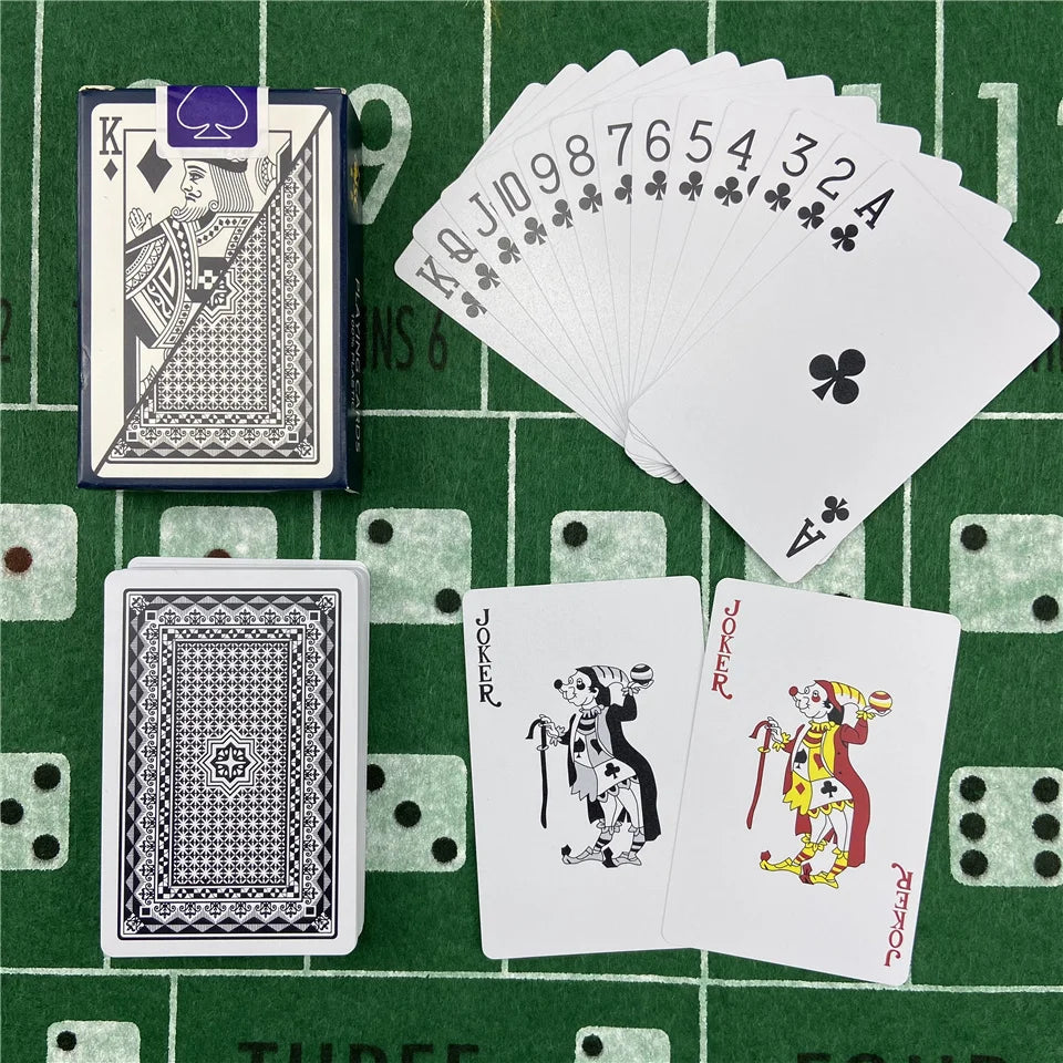 A green felt surface displays a deck of poker playing cards, including a full deck and several cards, set against a green gri