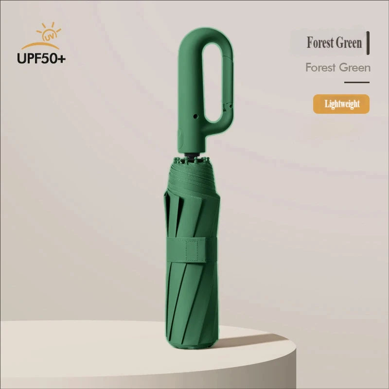 A forest green large automatic folding umbrella standing on a light-colored surface.