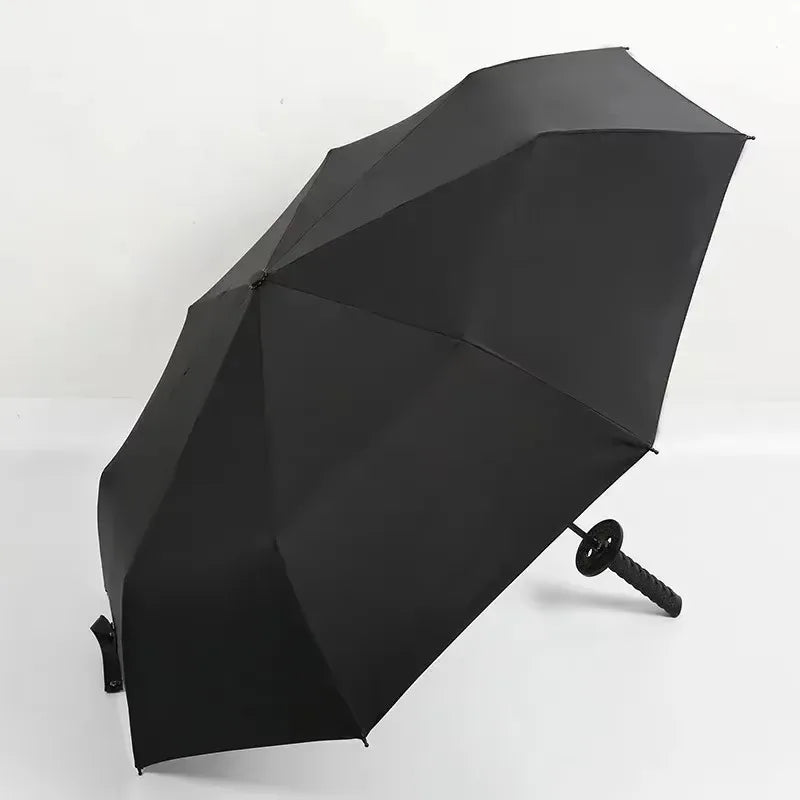 A black folding katana sword umbrella is shown open, angled downward against a white background.