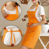 An orange oil-proof cooking apron worn over a white shirt, showing details of the fabric and tie closure.