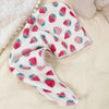 A pink and white strawberry print quick-drying hair towel headscarf lying on a light beige surface.