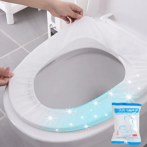 A white waterproof disposable toilet seat cover is being placed onto a toilet bowl.