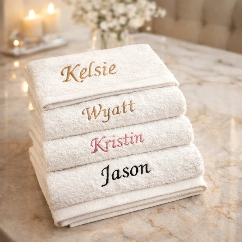 Stapel weiße Baumwollhandtücher mit eingestickten Namen: Kelsie, Wyatt, Kristin und Jason.