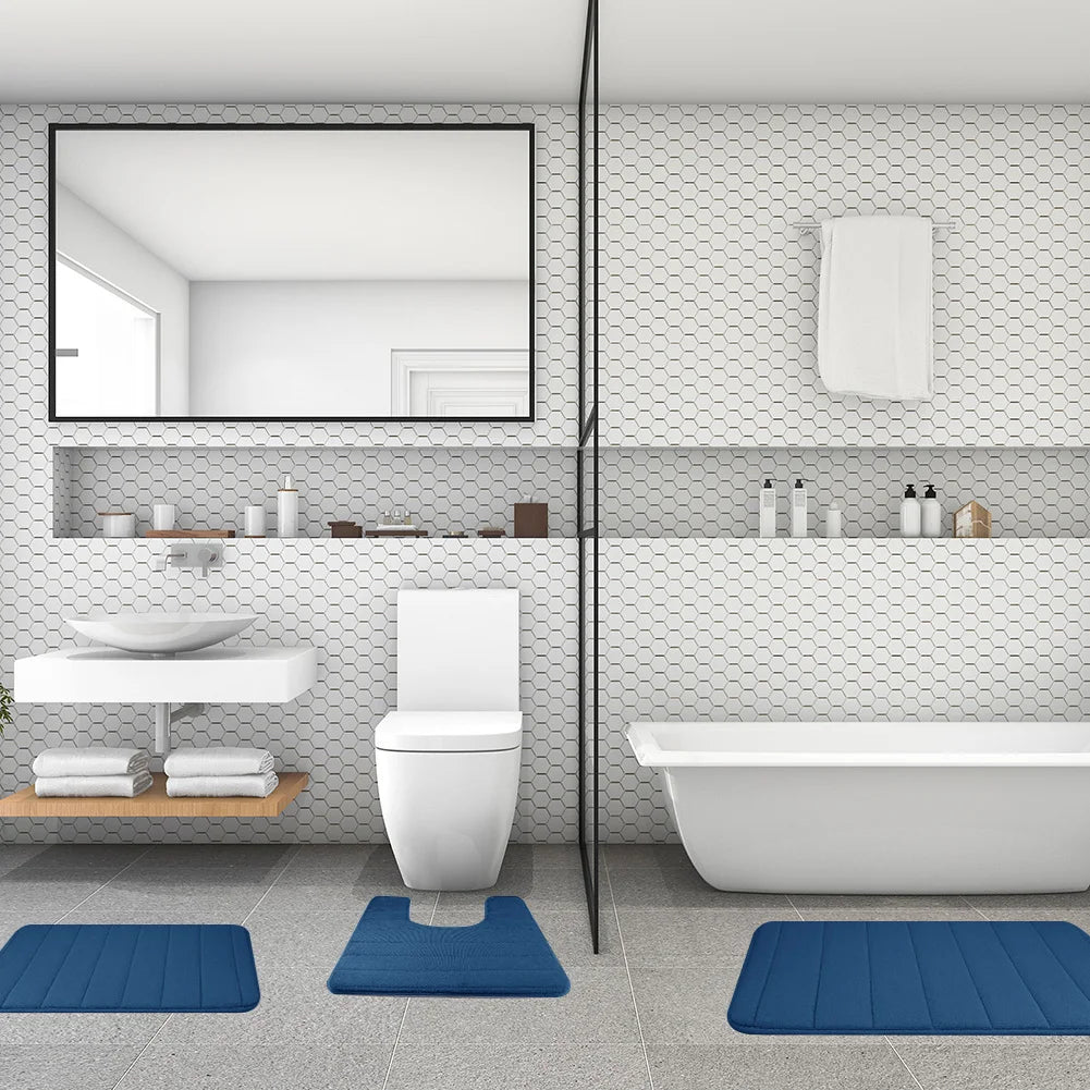 Modernes weißes Badezimmer mit Toilette, Waschbereich und Badewanne mit drei blauen Memory-Schaum-Matten.