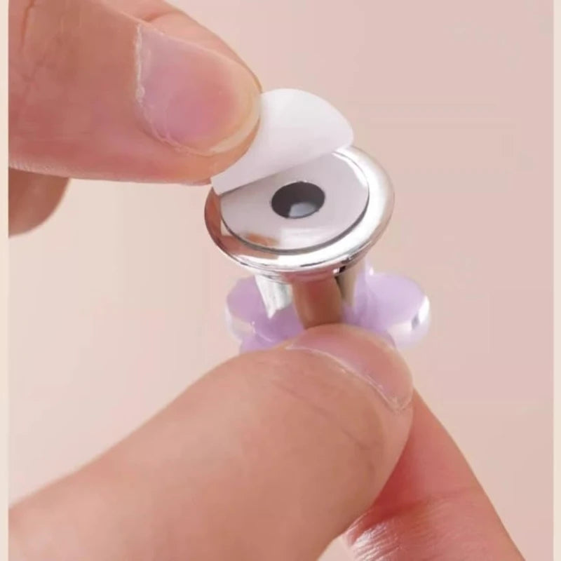 A hand is pressing a flower-shaped toilet flush button with a silver and white mechanism.