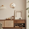 Horloge murale moderne en forme de lune avec accents dorés, suspendue au-dessus d'un meuble en bois et d'un art encadré.
