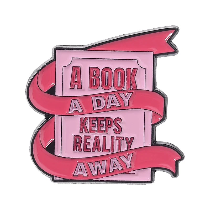 Pin de esmalte con texto que dice 'Un libro al día mantiene alejada la realidad' sobre fondo rosa con diseño de cinta roja.