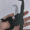 A hand holds a black wooden monkey-shaped key hanger decoration.