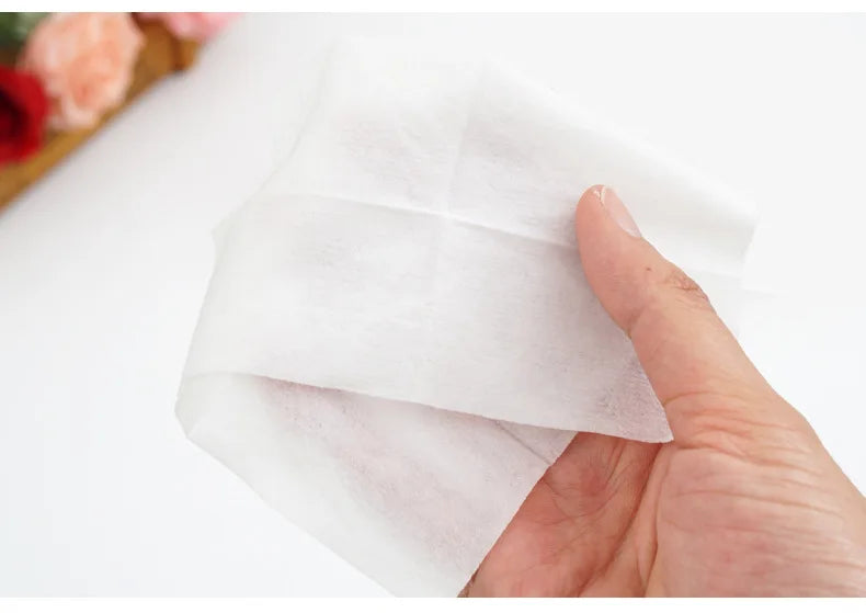 A hand is holding a white portable mini hand wipe for hygiene.