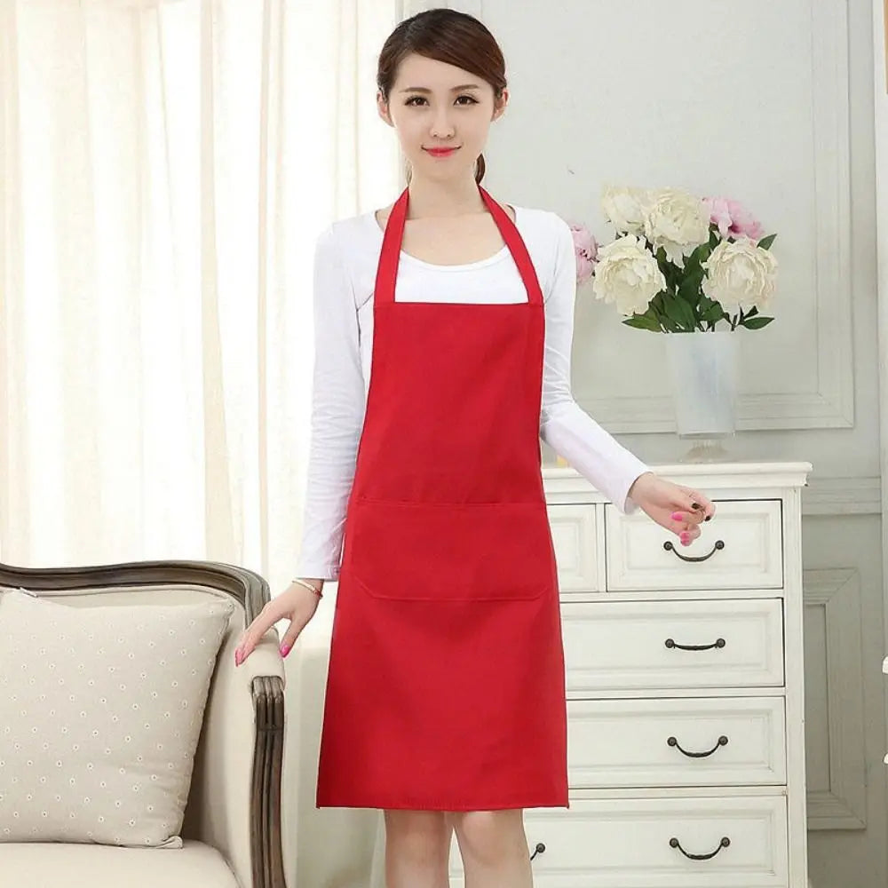 A woman models a red oil-proof cooking apron with pockets over a white shirt in a bright indoor setting.