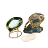 A decorative glass soap dish with a leaf shape holds a white bar of soap.
