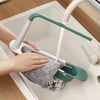 A hand is using an adjustable over-sink dish rack organizer to wash dishes in a kitchen sink.