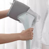 A hand is holding a light blue heat resistant ironing pad and iron, preparing to use it on a white garment.