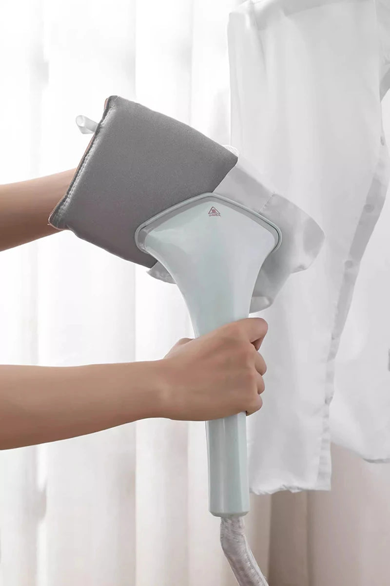 A hand is holding a light blue heat resistant ironing pad and iron, preparing to use it on a white garment.