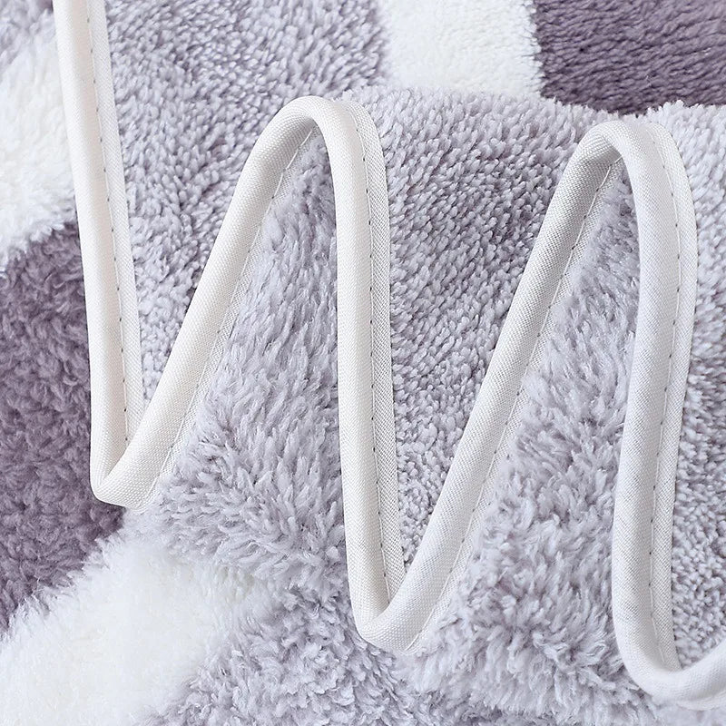 A close-up of a fluffy gray and white microfiber bath towel set with white straps.