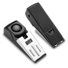 Un dispositivo de alarma para puertas portátil negro con una placa de plata y sensor de vibración.