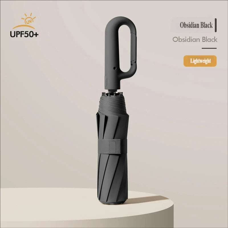 A black automatic folding umbrella is shown standing upright on a light surface.