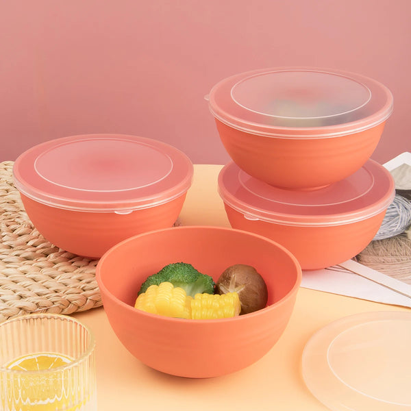 A set of orange reusable food storage bowls with clear sealing lids, containing yellow corn and green broccoli.