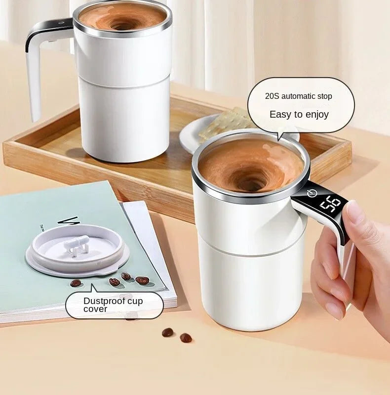 A white electric self-stirring coffee mug is shown next to a wooden tray and a notebook, demonstrating its use.