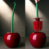 A green decorative cherry-shaped toilet brush set with a red handle and bristles against a neutral background.