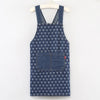 A dark blue denim apron with a repeating pattern of small white hearts and a chest pocket hanging on a wooden hanger.