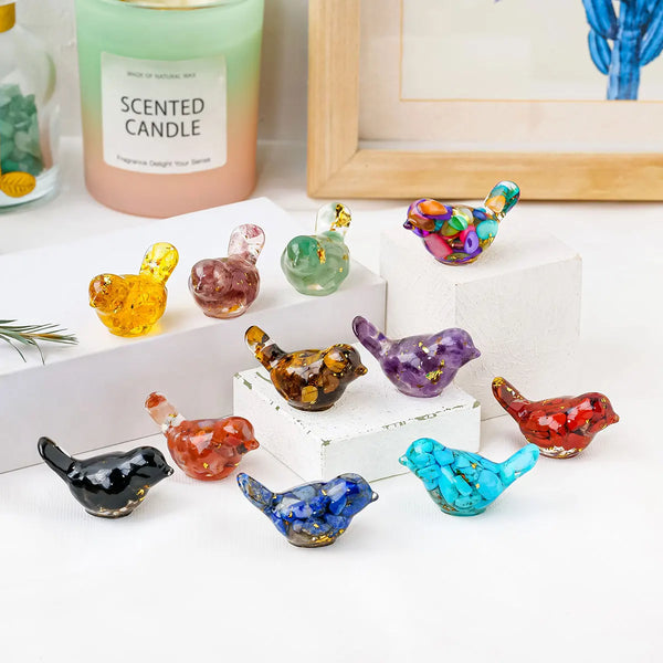 A collection of colorful crystal bird statues in various shades of green, purple, and orange displayed on a white surface.