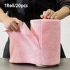 A hand is holding a roll of pink reusable microfiber cleaning cloths, showing the texture and size.