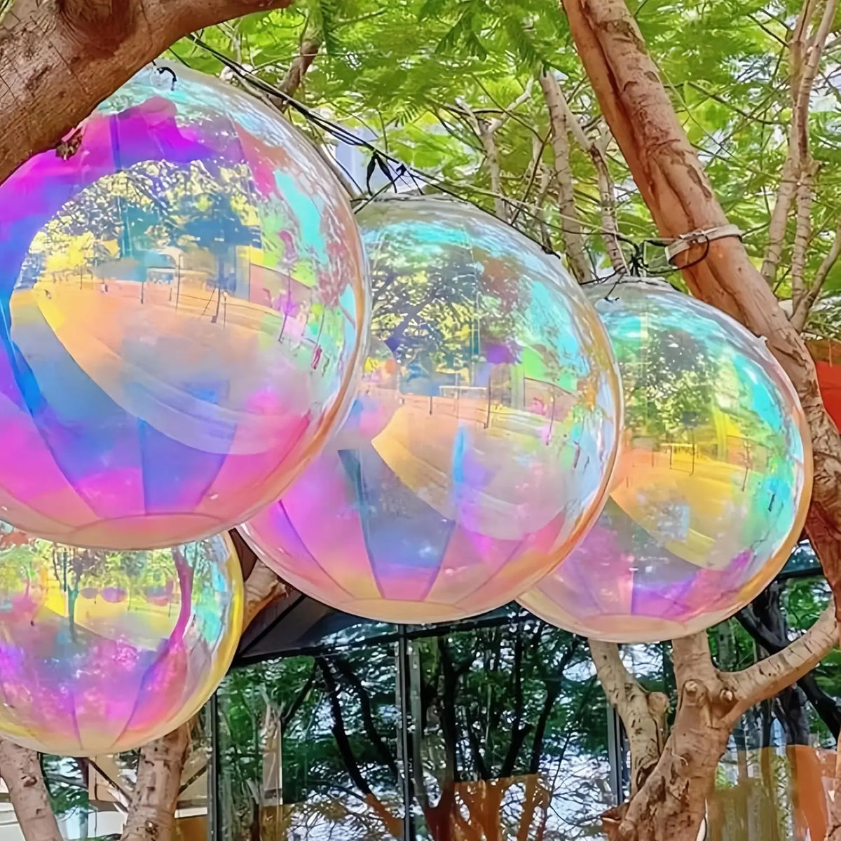 Ein Cluster irisierender holografischer Partyballons, an Ästen in einer Außenumgebung gebunden.