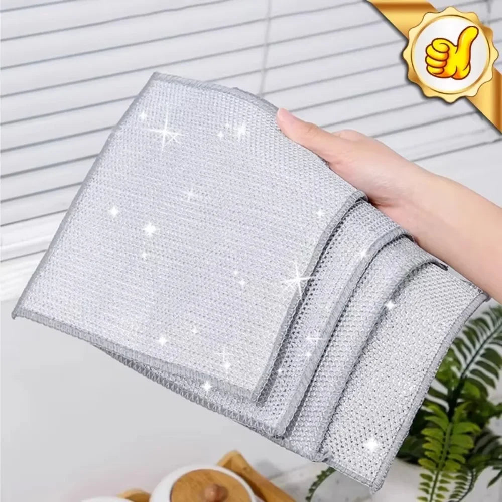 A hand is holding a stack of silver non-stick wire cleaning dish rags with sparkling details.