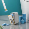 A white reusable toilet brush holder with blue cleaning brushes on a gray surface.