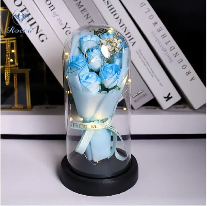 Ein Glasstrauß hellblauer Rosen in einem klaren Ständer auf einer weißen Oberfläche.