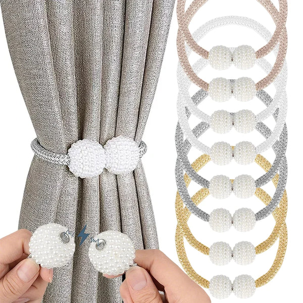 A set of pearl magnetic curtain tiebacks in white, gray, and gold colors shown against a beige curtain.