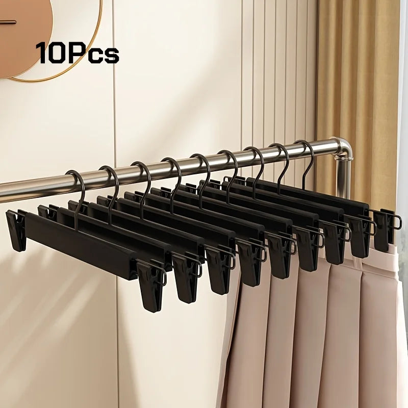 A set of ten black adjustable metal clothes hangers hanging from a chrome rod.