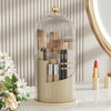 A clear glass organizer with a lid holds various makeup brushes and tools for rotating use.