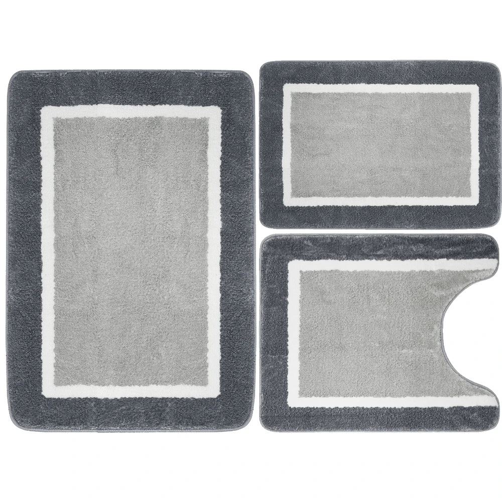 A set of three gray memory foam bathroom rugs, including a rectangular mat and two irregular shapes.