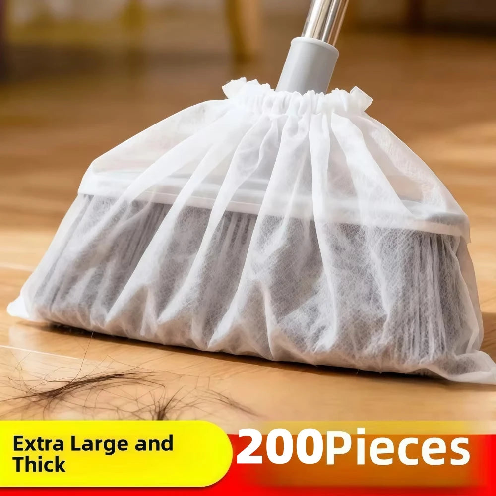 A white disposable broom cover made of sheer mesh fabric is shown on a wooden floor.