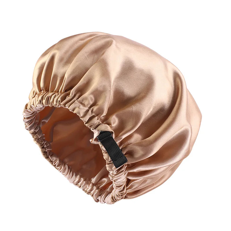 A beige satin sleep cap with a gathered brim and a black tie, designed for curly or natural hair.
