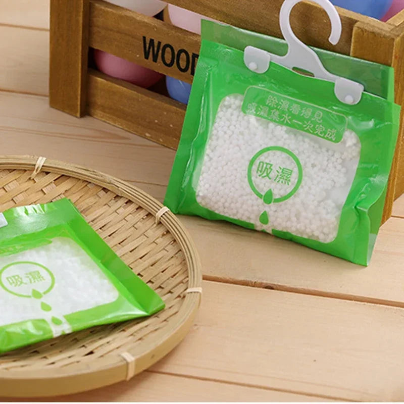 Green hanging bags filled with white moisture absorber pellets displayed in a wooden storage box.