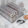 Clear plastic jewelry organizer boxes filled with various beads and stones resting on white fur